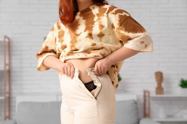 Image of woman trying to do her trousers up after pregnancy weight gain Telford